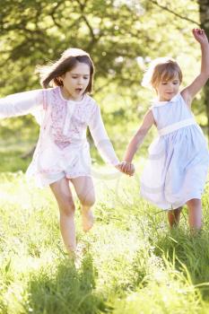 Two Young Girls Walking Through Summer Field Together