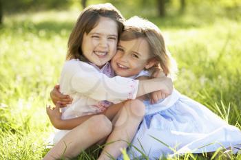 Two Young Girls Giving One Another Hug In Summer Field