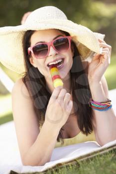 Woman Relaxing In Garden Eating Ice Lolly