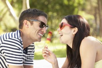Couple Relaxing Together In Garden Eating Ice Lolly