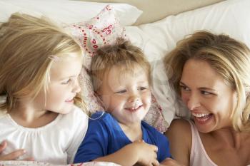 Mother And Children Relaxing Together In Bed