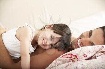 Father And Daughter Relaxing Together In Bed