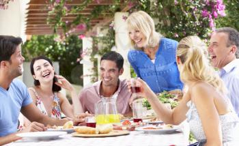 Group Of Young And Senior Couples Enjoying Family Meal