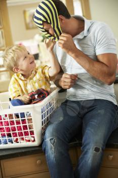 Father And Son Sorting Laundry Sitting On Kitchen Counter