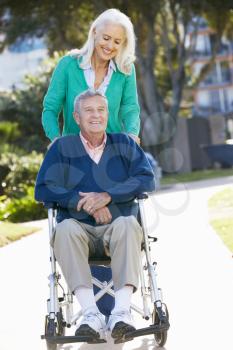 Senior Woman Pushing Husband In Wheelchair