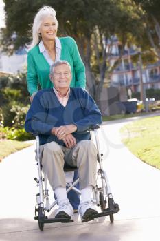 Senior Woman Pushing Husband In Wheelchair
