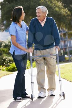 Carer Helping Senior Man With Walking Frame