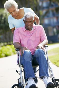 Senior Woman Pushing Unhappy Husband In Wheelchair