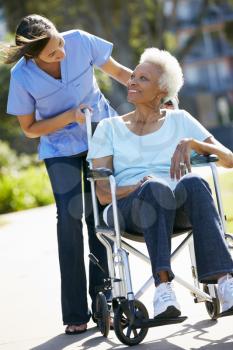 Carer Pushing Senior Woman In Wheelchair
