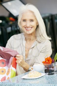 Senior Woman Enjoying Snack At Outdoor Caf After Shopping