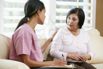 Nurse Discussing Records With Senior Female Patient During Home Visit