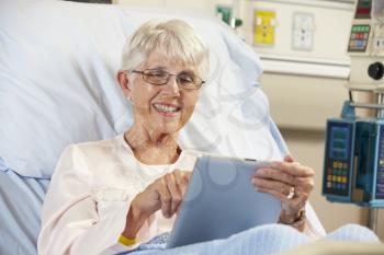 Senior Female Patient Relaxing In Hospital Bed With Digital Tablet