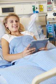 Teenage Female Patient Relaxing In Hospital Bed With Digital Tablet