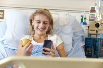 Teenage Female Patient Using Mobile Phone In Hospital Bed