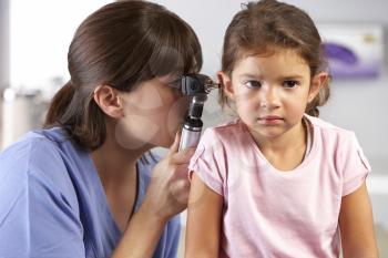 Doctor Examining Child's Ears In Doctor's Office