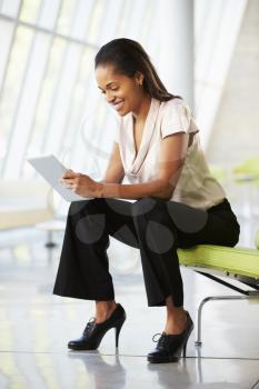 Businesswoman Sitting On Sofa In Office Using Digital Tablet