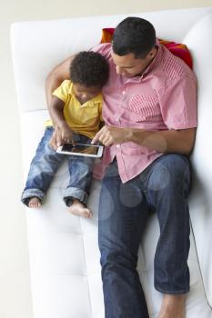 Overhead View Of Father And Son On Sofa Using Digital Tablet