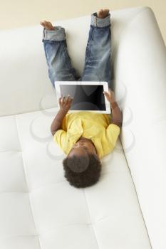 Overhead View Of Boy On Sofa Playing With Digital Tablet