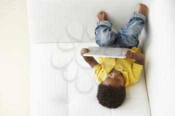 Overhead View Of Boy On Sofa Playing With Digital Tablet