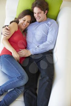 Overhead View Of Man Relaxing On Sofa With Pregnant Wife