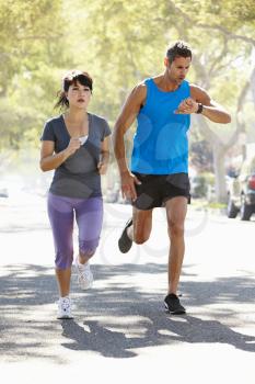 Woman Running Along Street With Personal Trainer