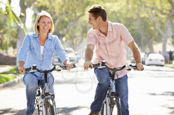Couple Cycling On Suburban Street