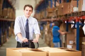 Businessman Pulling Pallet In Warehouse
