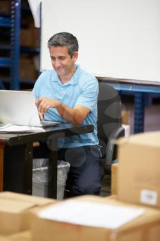 Worker In Distribution Warehouse Using Laptop
