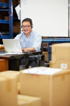 Worker In Warehouse Wearing Headset And Using Laptop