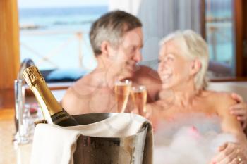 Senior Couple Relaxing In Bath Drinking Champagne Together