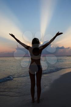 Silhouette Of Woman With Outstretched Arms On Beach