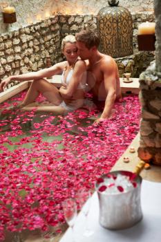 Couple Relaxing In Flower Petal Covered Pool At Spa