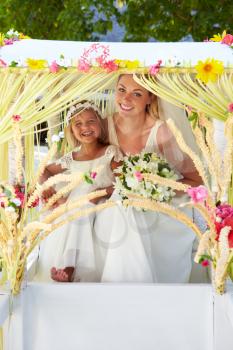 Bride And Bridesmaid Sitting Under Decorated Canopy