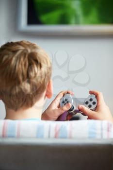 Rear View Of Boy Holding Controller Playing Video Game