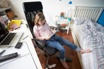 Girl Using Digital Tablet In Bedroom