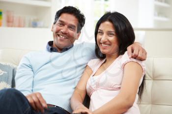 Indian Couple Sitting On Sofa Watching TV Together