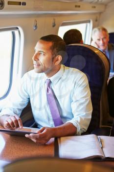 Businessman Commuting On Train Using Digital Tablet