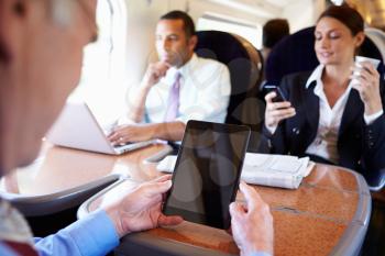 Businesspeople On Train Using Digital Devices