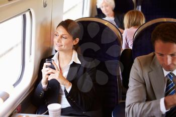 Businesswoman Commuting To Work On Train Using Mobile Phone