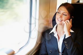 Businesswoman Commuting To Work On Train Using Mobile Phone