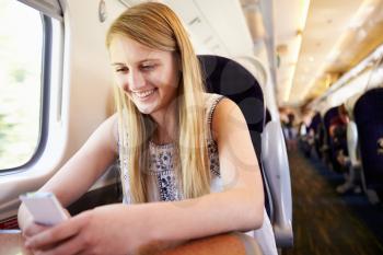 Teenage Girl Using Mobile Phone On Train Journey