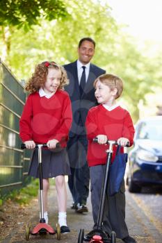 Children Riding Scooters On Their Way To School With Father