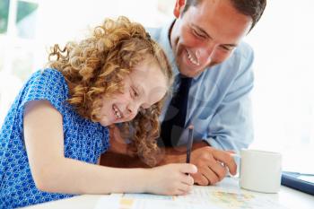 Father Helping Daughter With Homework In Kitchen