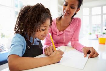 Mother Helping Daughter With Homework In Kitchen