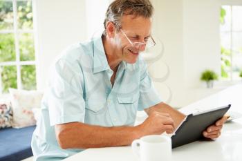 Middle Aged Man Using Digital Tablet Over Breakfast
