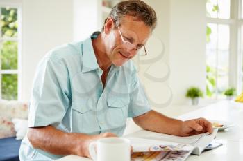 Middle Aged Man Reading Magazine Over Breakfast