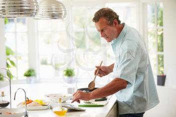 Middle Aged Man Following Recipe On Digital Tablet