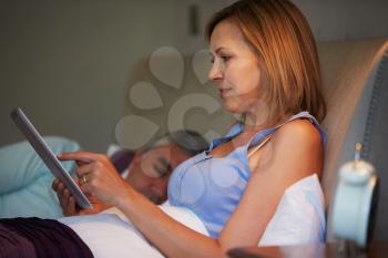 Middle Aged Couple In Bed With Woman Using Tablet Computer