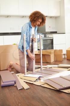 Woman Putting Together Self Assembly Furniture In New Home