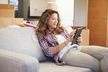 Woman Relaxing On Sofa With Digital Tablet In New Home